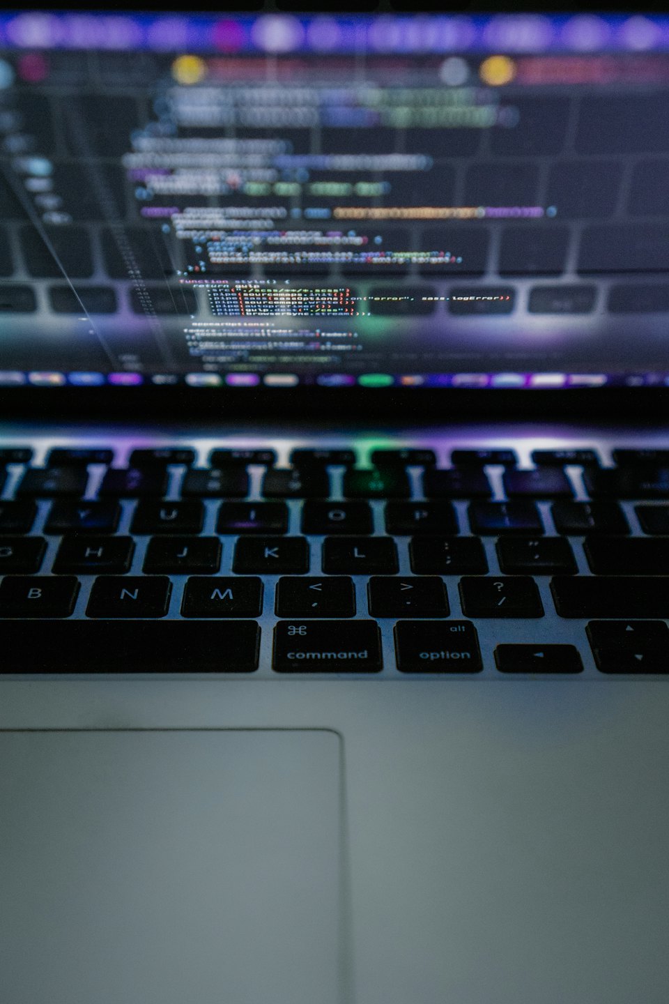 Laptop-Bildschirm mit buntem Code und beleuchteter Tastatur.